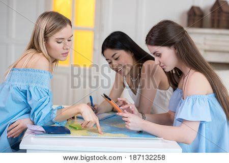 Young Beautiful Women Travelers Looking At World Map At Room, Best Friends Girls