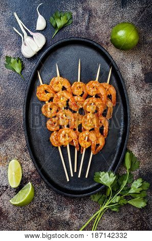 Grilled spicy lime shrimp skewers with creamy avocado garlic cilantro sauce. Top view overhead flat lay