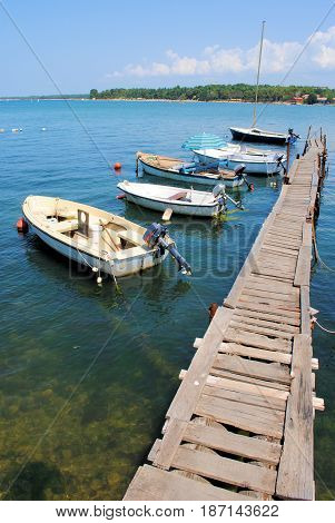 Five small boats attachted to a wooden pier