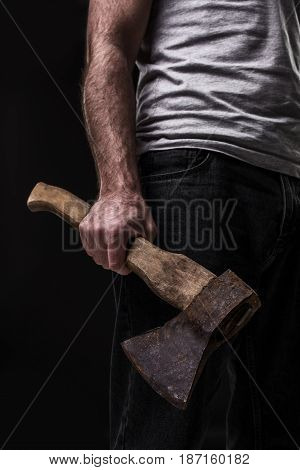 A man holds an ax in his hands against on black background. Criminal