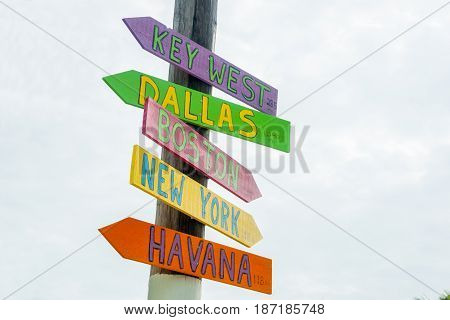 Colorful rustic direction signs on pole to major cities at Little Torch Key Maimi