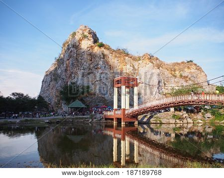 Mountain and long vintage bridge across lake with reflection at Khao Ngoo Rock Park or Thueak Khao Ngu Ratchaburi Province Thailand.