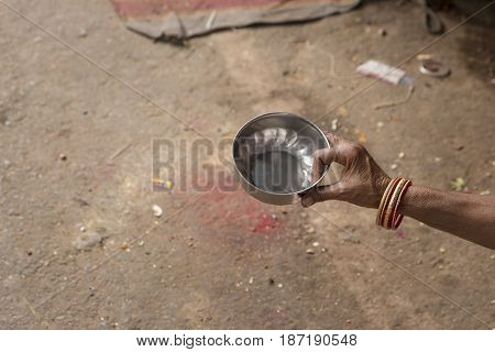 small water dipper for begging in hand of indian beggar