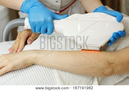Hardware cosmetology. Depilation. Elos hair removal. Man is unrecognizable. Beautiful female hands.
