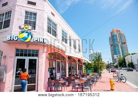 Miami, USA- June 28, 2016; Women approaches door of Big Pink retro era restaurant on Collins Avenue with empty table outside on pavement.