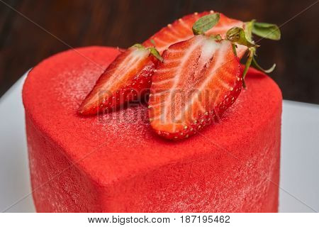 Red strawberry cake in the shape of heart on Valentine's Day on wooden background