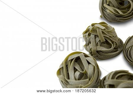 Overhead view of green tagliatelle arranged on white background