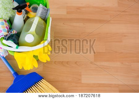 High angle view of cleaning equipment in bucket by broom on hardwood floor