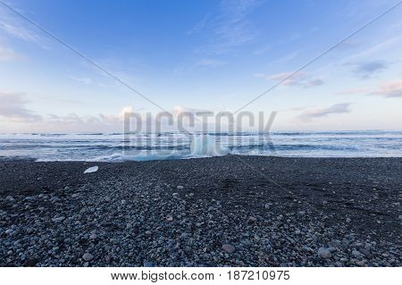 Small ice on black rock sand beach seacoast skyline Iceland natural landscape background