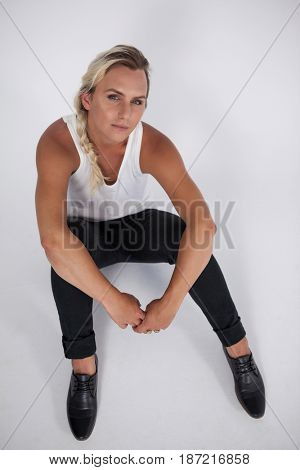 High angle portrait of transgender woman sitting over gray background