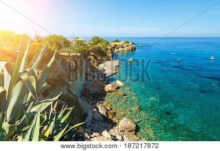 Waves break on rocky shore. Coast and beach resort village. Road along a rocky cliff. Tourist beach resort in village Crete island, Greece,