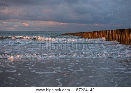 Sunset on piles at the North Sea beach of Cadzand Holland