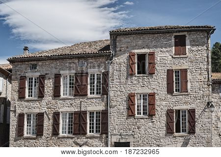 Windows with shutters in stone houses in the town of Largentiere in France
