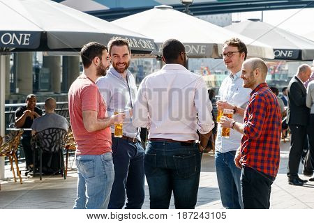 Group Of Young Men Drinking At A Dockside Bar