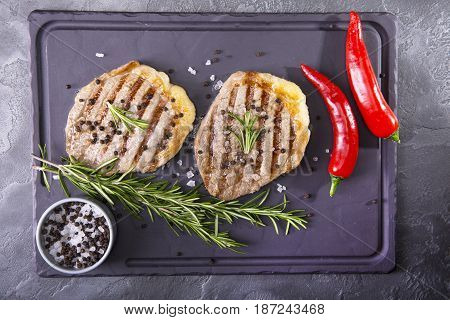 Top view of two grilled beef medallion steaks on a black wooden background