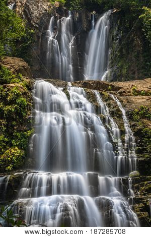 Double waterfalls in Costa Rica with grey rocks and green bushes and trees