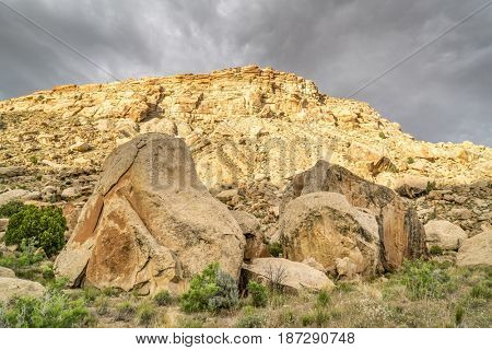 Book Cliffs under stormy clouds - desert landscape of eastern Utah with a cliffs and boulders