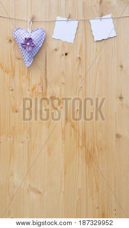 Two jagged note with clothes pegs and a checkered heart of fabric on a cord on wood