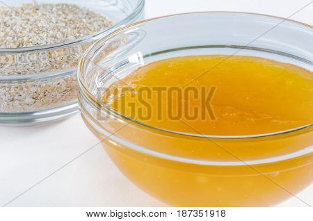 Oat bran and honey in a glass bowl isolated on white background. Closeup shot. Healthy food concept.