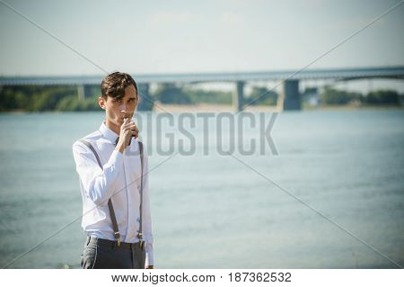 Young Skinny Man, Elegantly Stylishly Dressed In White Shirt, Trousers With Suspenders And Bow Tie.