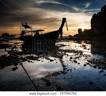 traditional long tail boat silhouette at low tide in sunset liights on Ton Sai beach, Thailand