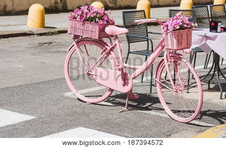 Alghero Italy - May 05 2017: Pink bike with flowers parked on the street