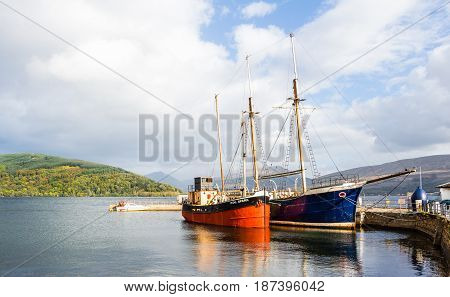 INVERARAY ARGYLL AND BUTE SCOTLAND - SEPTEMBER 26 2014: couple of colourful vintage boat and sailboat docked at the harbour in the waters of Loch Fyne in a bright sunny summer day.