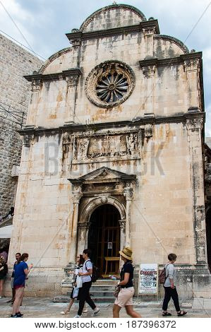 DUBROVNIK CROATIA - JULY 16th 2016: tourists passing by Saint Saviour church's front gate and façade of Renaissance architecture at Stradun street starting square in the Old Town.