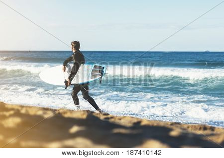 Surfer man holding surfboard on background sea scape sand beach coastline. Panorama horizon perspective view ocean sunlight. Travel summer sport concept backdrop sunny waves seascape mock up