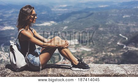 Hipster young girl with backpack and sun glasses looking on observation deck and planning travel plan. View tourist traveler on background panoramic view of the city mockup summer in Barcelona