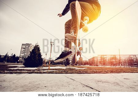 Man young skateboarder legs skateboarding at skatepark On Sunset. Concept tricks and jumping on a skateboard