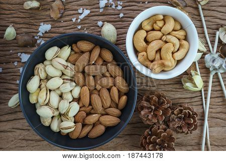 appetizer roasted healthy delicious salt pistachios cashew nuts and almonds food in black bowl on wooden table background.