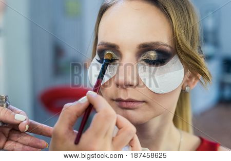 closeup view of Make-up artist doing smoky eyes makeup to beautiful young girl in the studio Dressing room