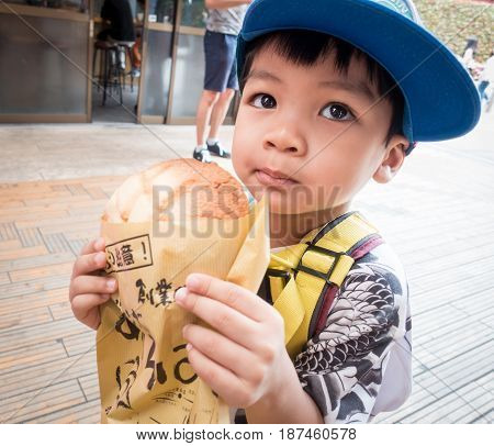 Tokyo Japan - May 1 2017: Asian Kid is eating Asakusa's Famous Melonpan bread.