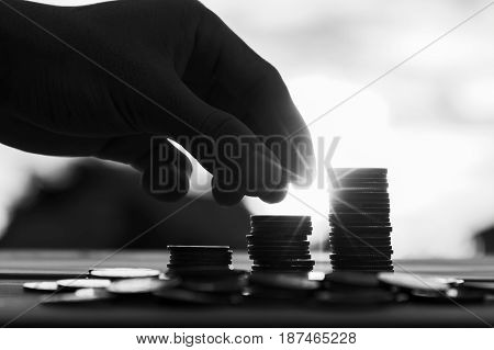 Saving money concept preset by Male hand putting money coin stack growing business. Close up of hand on sunset background Business Finance and Money concept Save money for prepare in the future