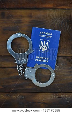 A Ukrainian Passport With Police Handcuffs Lies On A Wooden Table. Problems With The Law During The