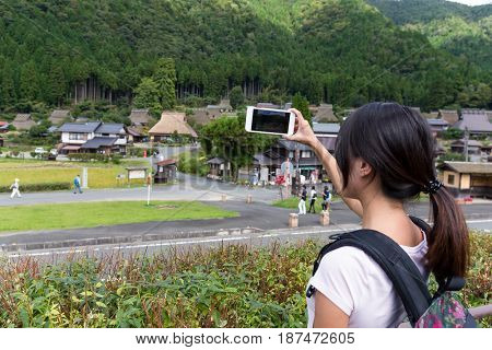 Woman taking photo with cellphone in miyama of Japan