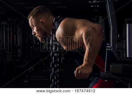 Weightlifter with a huge metal chain around his neck. Push-ups on the uneven bars in the gym