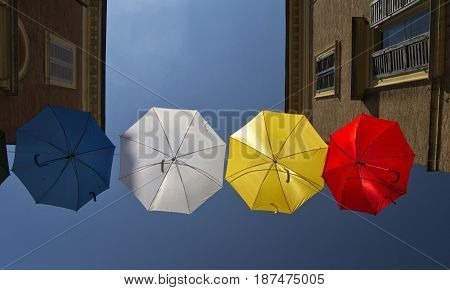 umbrellas of different colors over the street with blue sky as background