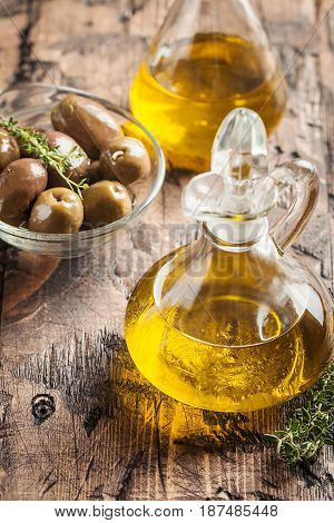 olive oil in glass bottle and olives over old wooden table