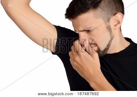 Portrait of young man smelling his armpit. Isolated white background.