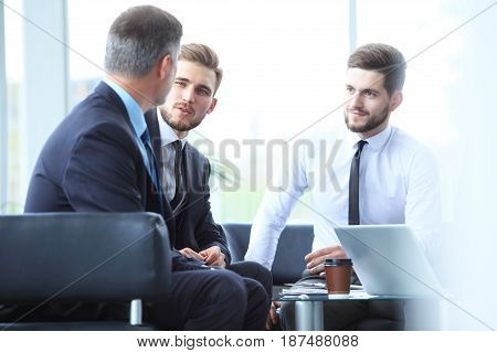 Mature businessman using a digital tablet to discuss information with a younger colleague in a modern business lounge