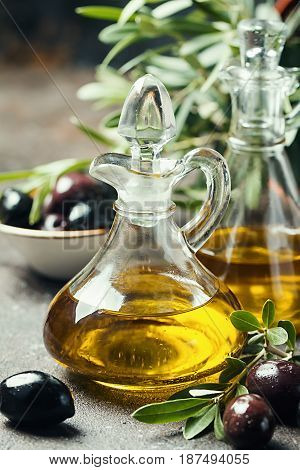 Olive oil in a glass bottle and olive branch on brown stone table