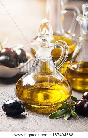 Olive oil in a glass bottle and olive branch on brown stone table