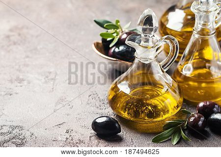 Olive oil in a glass bottle and olive branch on brown stone table