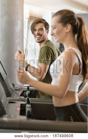 Determined young man smiling while running on treadmill during high-intensity interval training