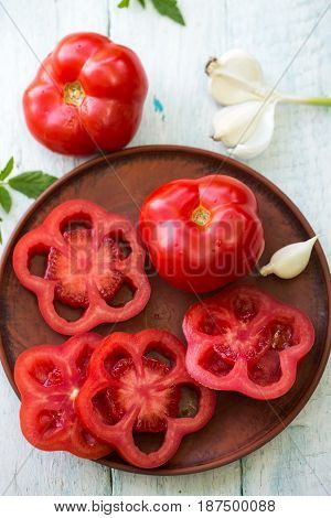 Fresh red tomato on a plate with garlic