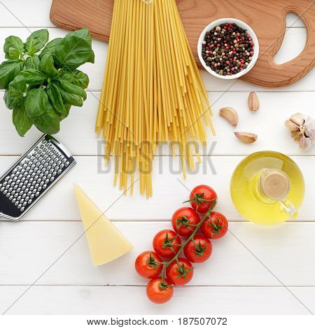 Dry Pasta Bucatini Or Spaghetti With Basil, Oil, Cheese, Tomatoes On White Wooden Background.