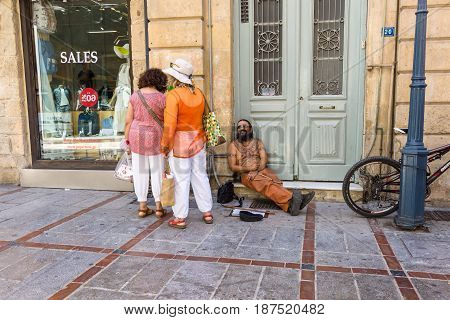 HERAKLION GREECE - JULY 09 2016: Crete. Joyful homeless man on a shopping street in the historic center of the city. Heraklion - the largest city on the island.