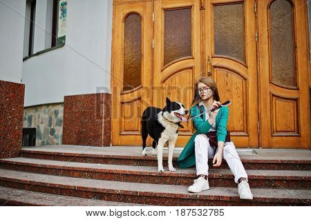 Trendy Girl At Glasses And Ripped Jeans With Russo-european Laika (husky) Dog On A Leash, Against Wo